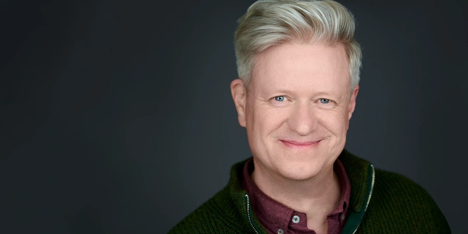 Peter Nutkins, headshot photographer, in a navy suit on a dark background.