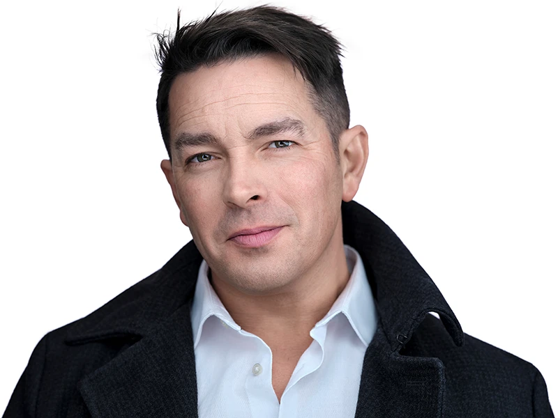 Professional headshot with confident, natural expression on a dark grey background