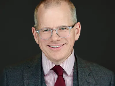 Executive headshot showing confidence and approachability against dark studio background