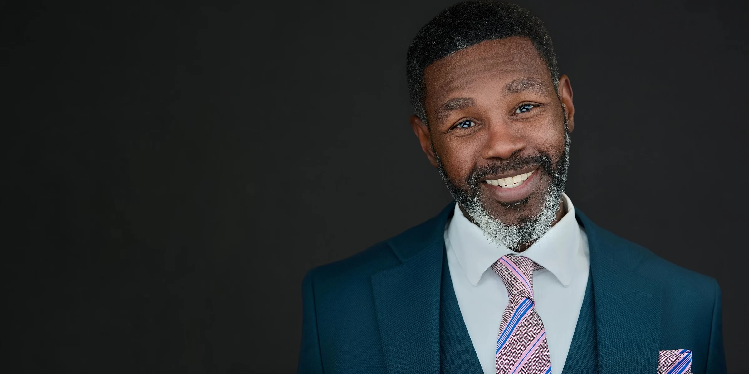 Professional headshot of a London business leader on a dark background with clear space for headline text.