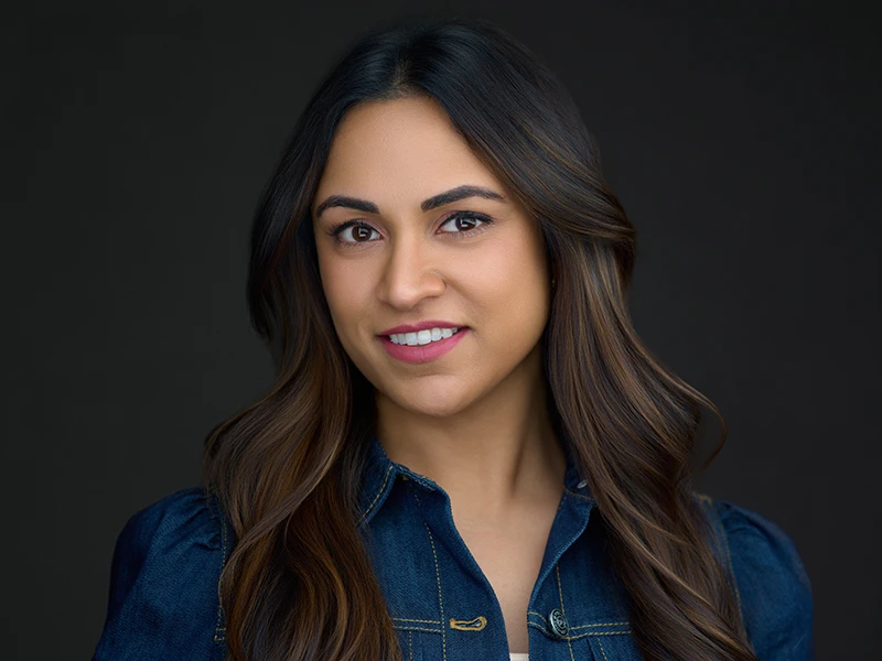 Modern headshot of a woman in a denim shirt on a dark background