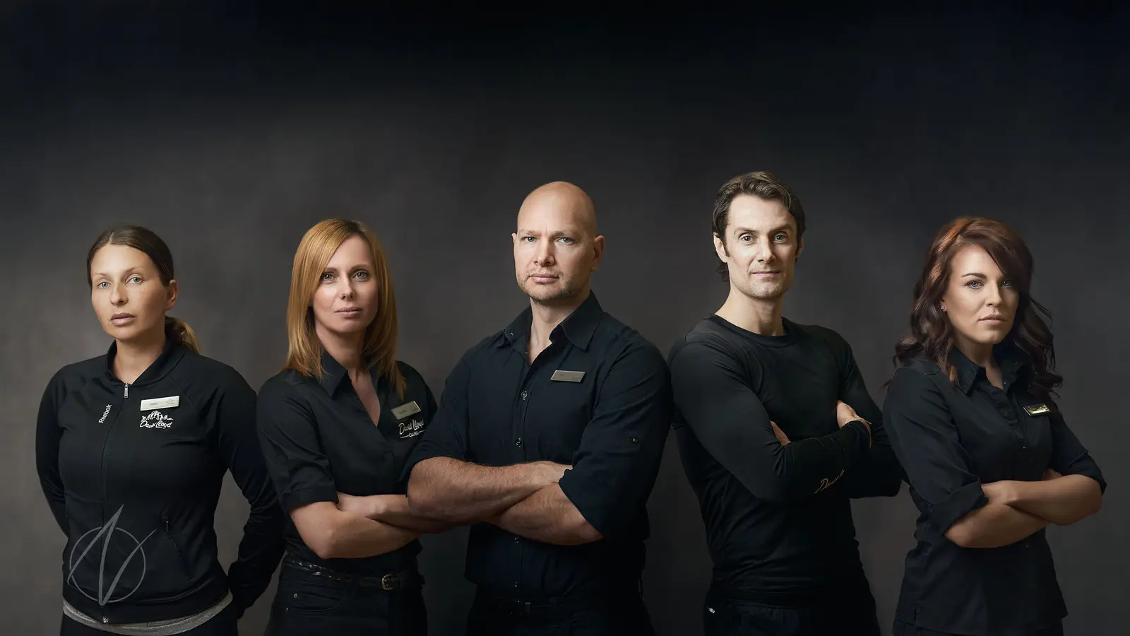 Five-person business team with crossed arms creating a strong unified professional image