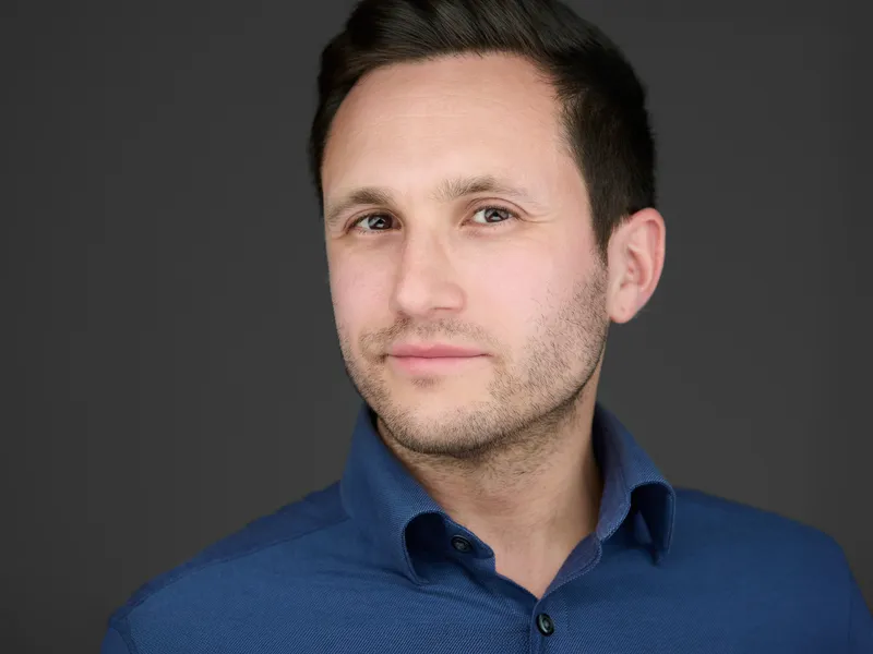 Professional man in navy button-down shirt with subtle beard, thoughtful expression