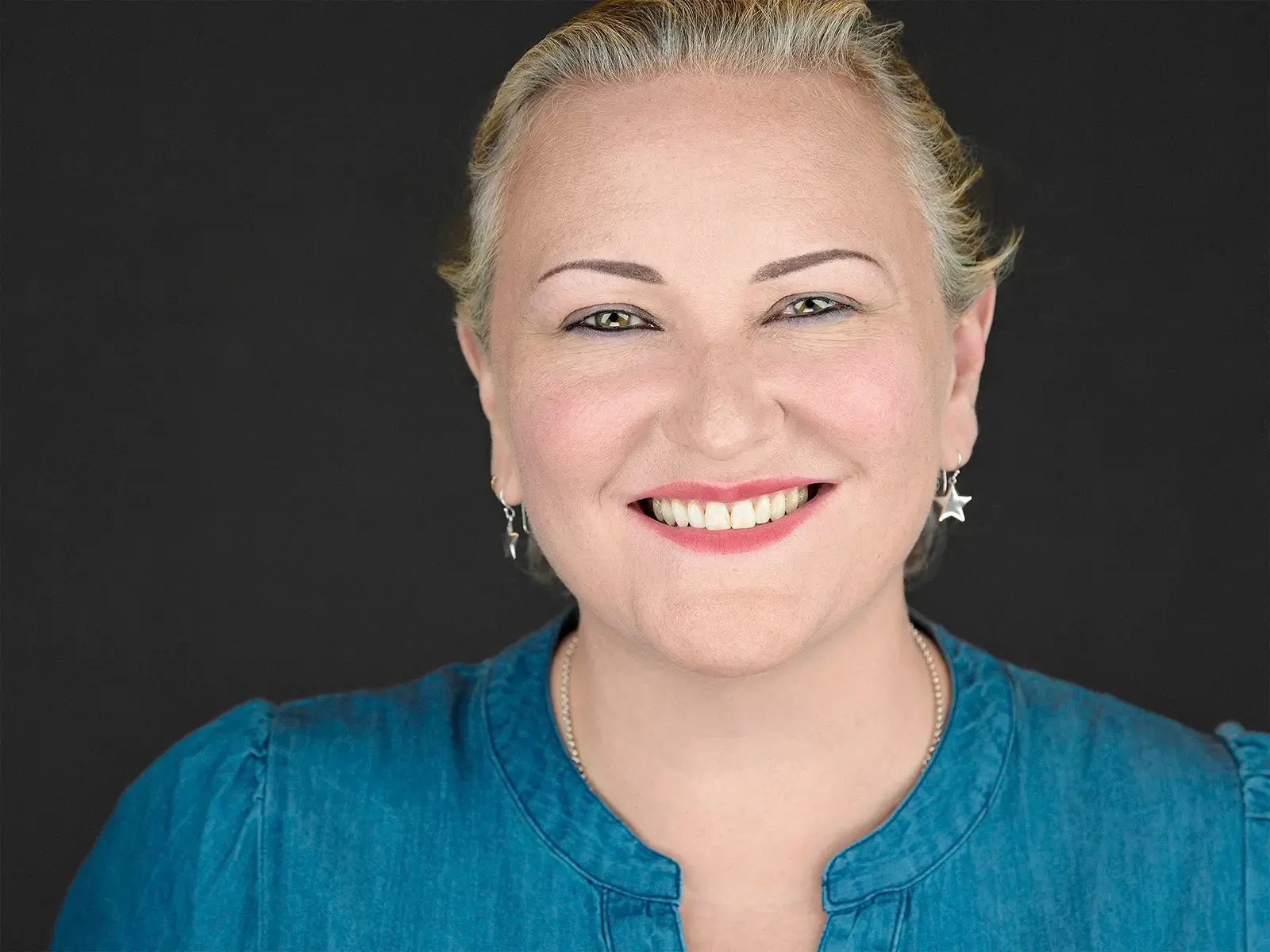 Woman in denim with star earrings showing how professional headshots can be both relaxed and polished