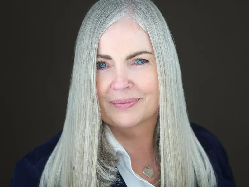 Executive woman with long blonde hair in navy blazer over white shirt, confident professional demeanor showcasing versatile business looks