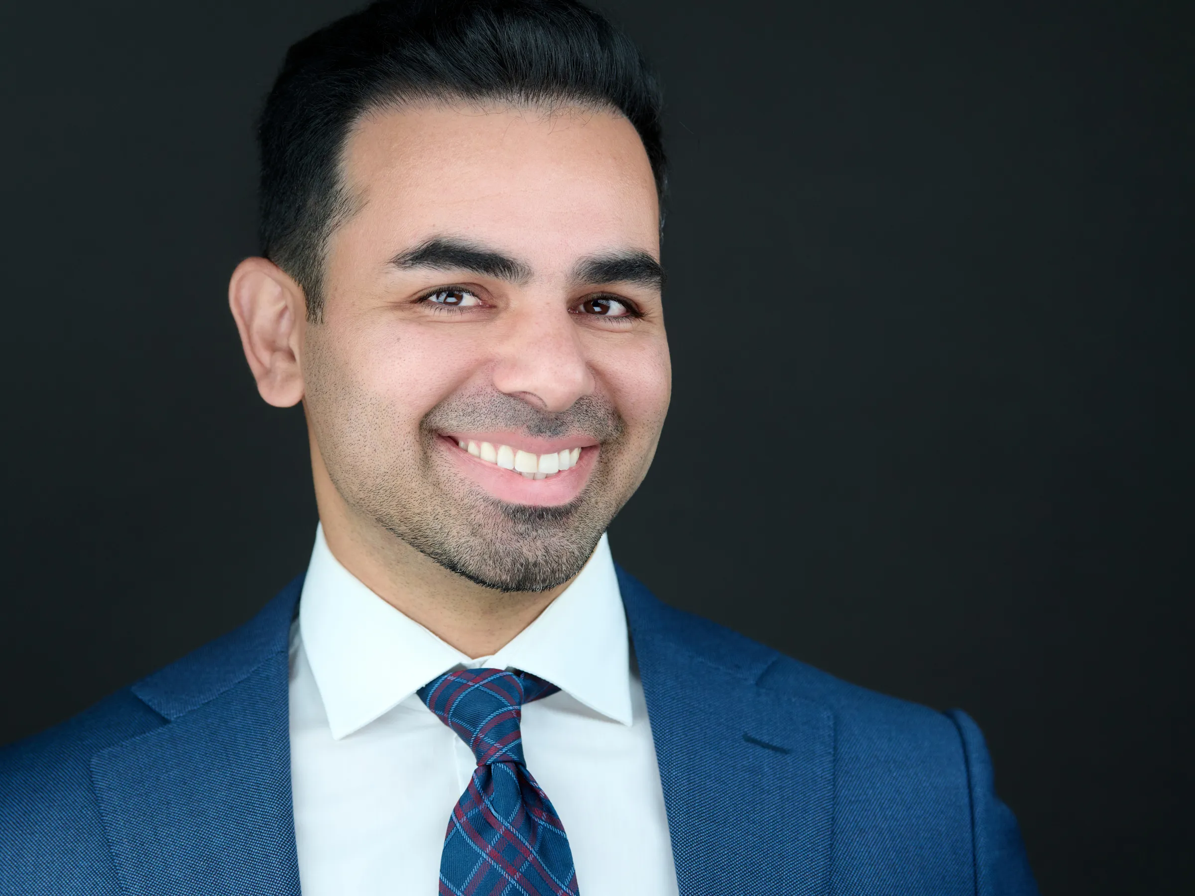 Primary headshot of Ben Rahmani with confident expression on a dark background