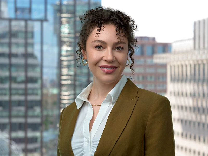 The same headshot with the Canary Wharf window view behind, the background blur matched to the original