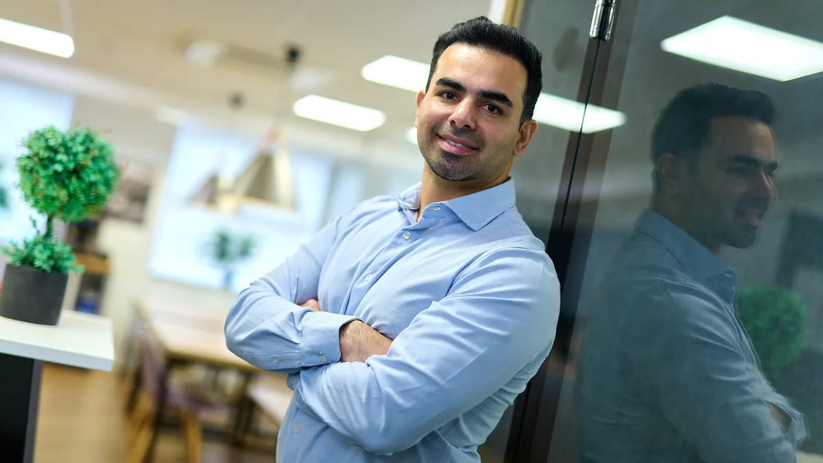 Professional leaning against a glass wall with folded arms in a relaxed pose