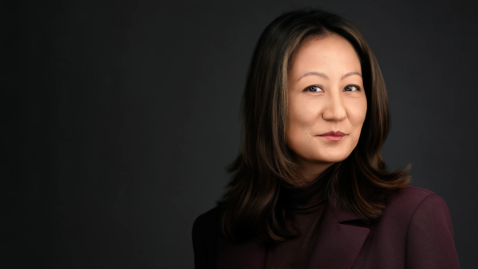 Professional headshot of a London executive in a dark blazer, photographed on a dark studio background.