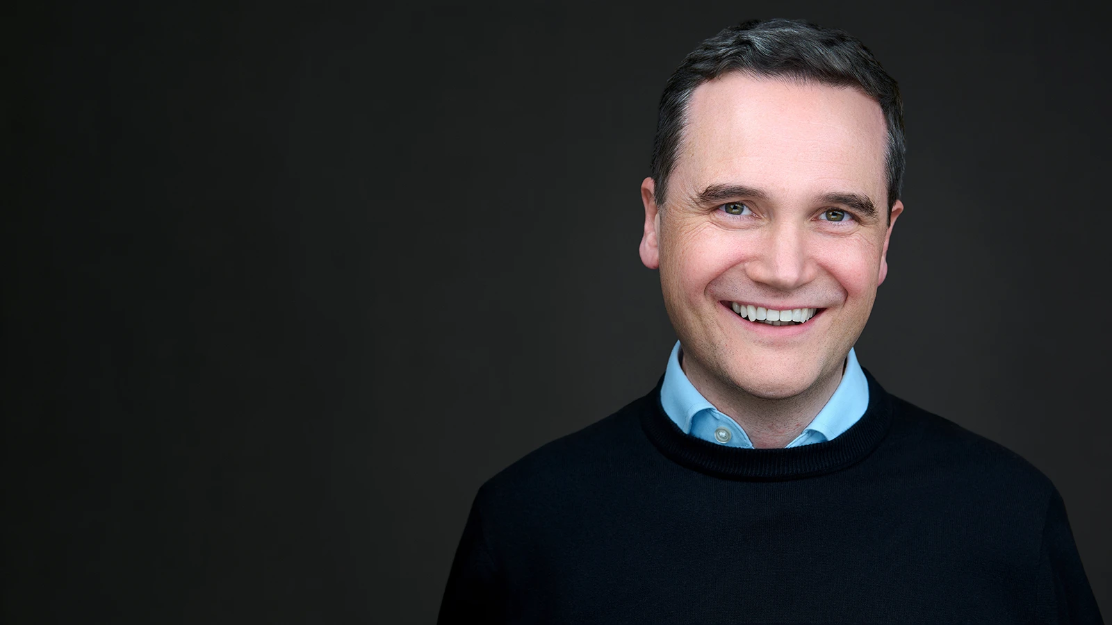 Professional headshot taken on location in Salisbury, South Wiltshire — confident expression, dark studio background, natural light