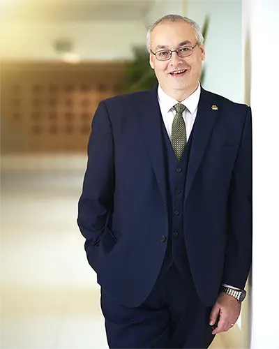 Man in a blue suit leaning against an office wall, corporate headshot in Exeter