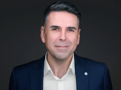 Man in open-collar blazer, engaged expression, dark studio background