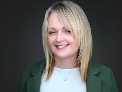 Woman in blazer over blouse, warm natural smile