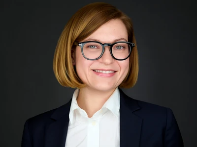 Woman in blazer and dress shirt wearing glasses, approachable professional expression