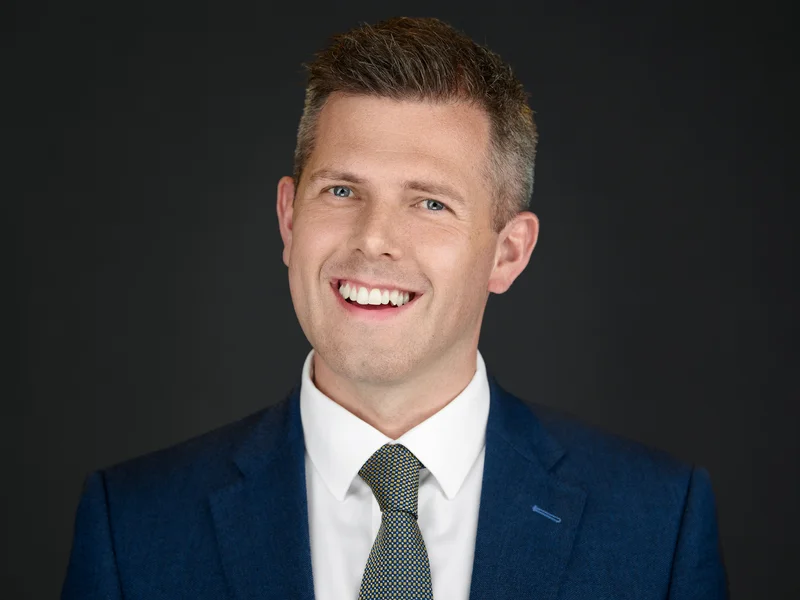 Professional man in a dark suit, clean business portrait with warm expression