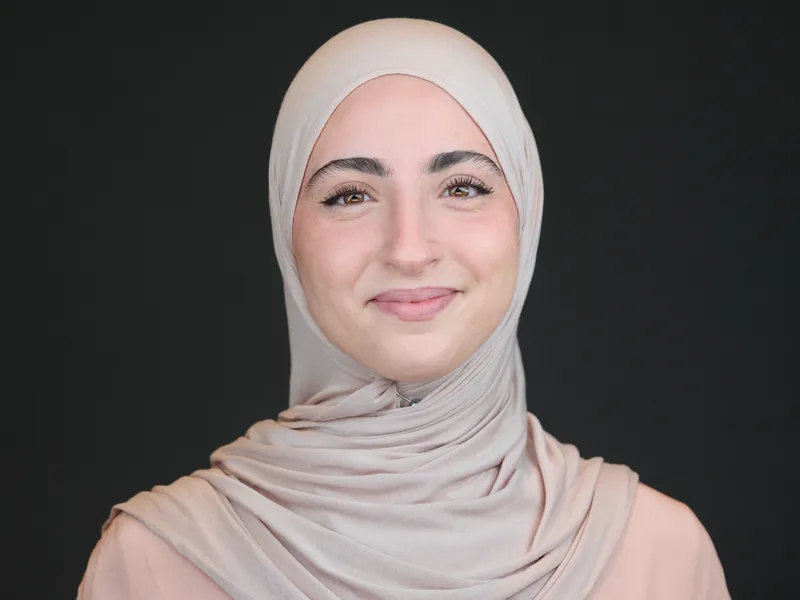 Woman in a hijab with a warm smile, studio business portrait on a dark background