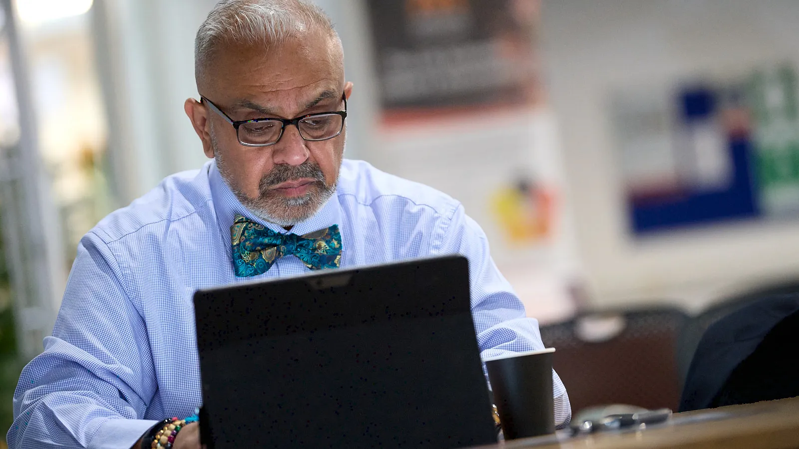 Consultant in glasses and a bow tie working at a laptop, focused expression