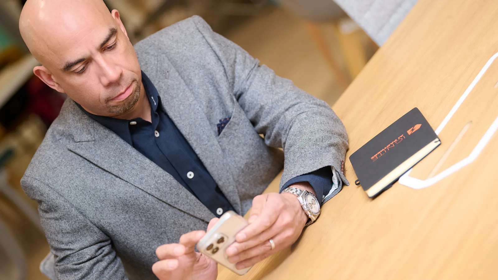 Man in a grey blazer on a phone call at a desk, working portrait