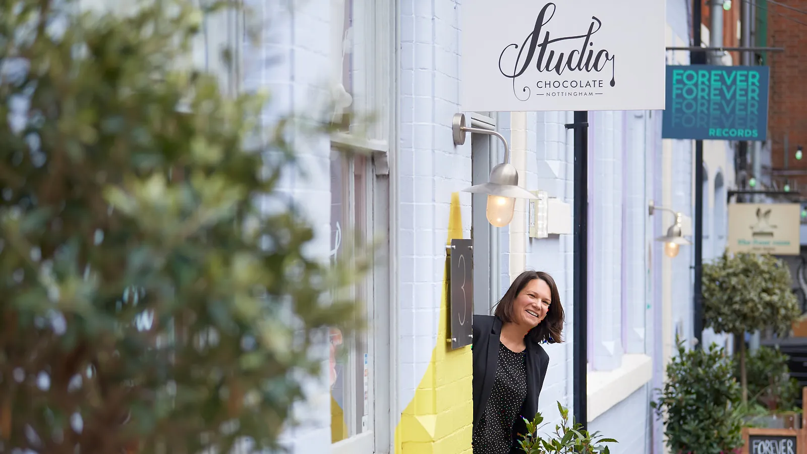 Woman in a black blazer smiling on a high street, personal branding on location